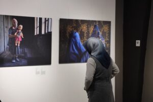 Sanat sergisi görünen kadın izleyici, çerçevede portre ve yüz detaylarıyla fotoğraflar.