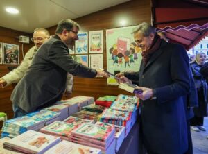 Otomatik taslak ile kitap ve dergi tanıtımı yapan kişiler, basın merkezi etkinliğinde kitapları ince.